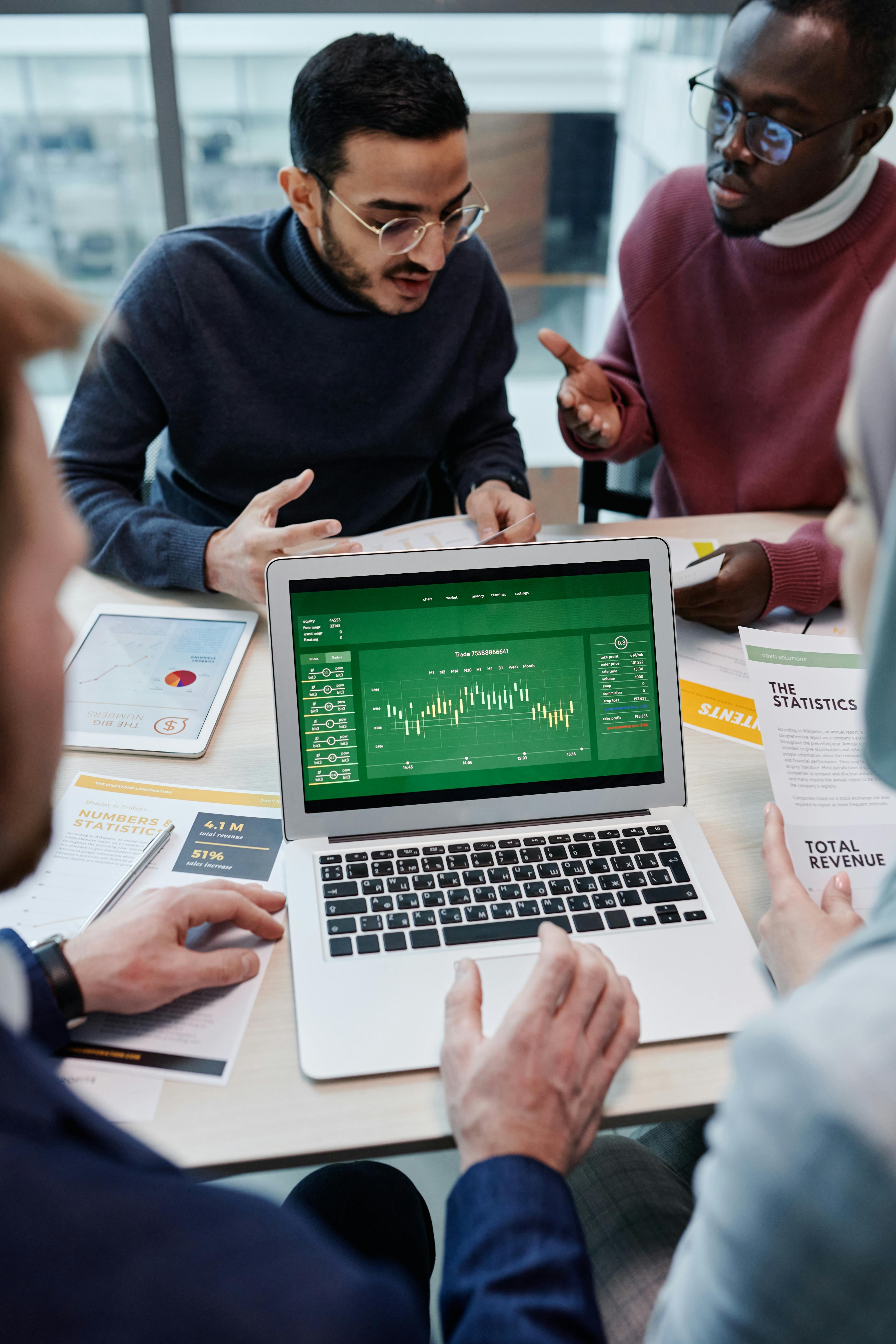 Professionals discussing market data on a laptop representing business innovation and emerging technology